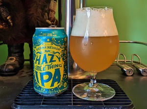 A bottle of Sierra Nevada Hazy Little Thing next to a tulip glass filled with the bottle's contents, a hazy, light copper beer with a thick white head