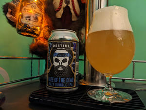 A can of Destihl Haze of the Dead next to a tulip glass filled with its contents, a coppery, hazy beer with a large, fluffy white head